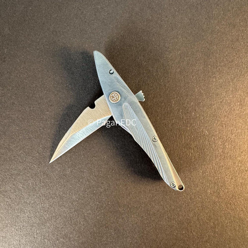 Petrified Fish PFE10 Hummingbird mini folding knife with M390 blade and titanium handle on dark background