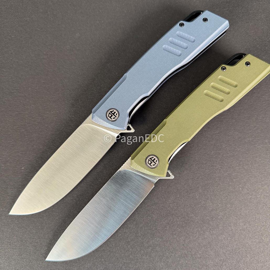 Two Loco PFB02 folding knives displayed open on a dark background, featuring satin-finished D2 steel blades and textured G10 handles in blue and olive green, designed for rugged everyday carry use.