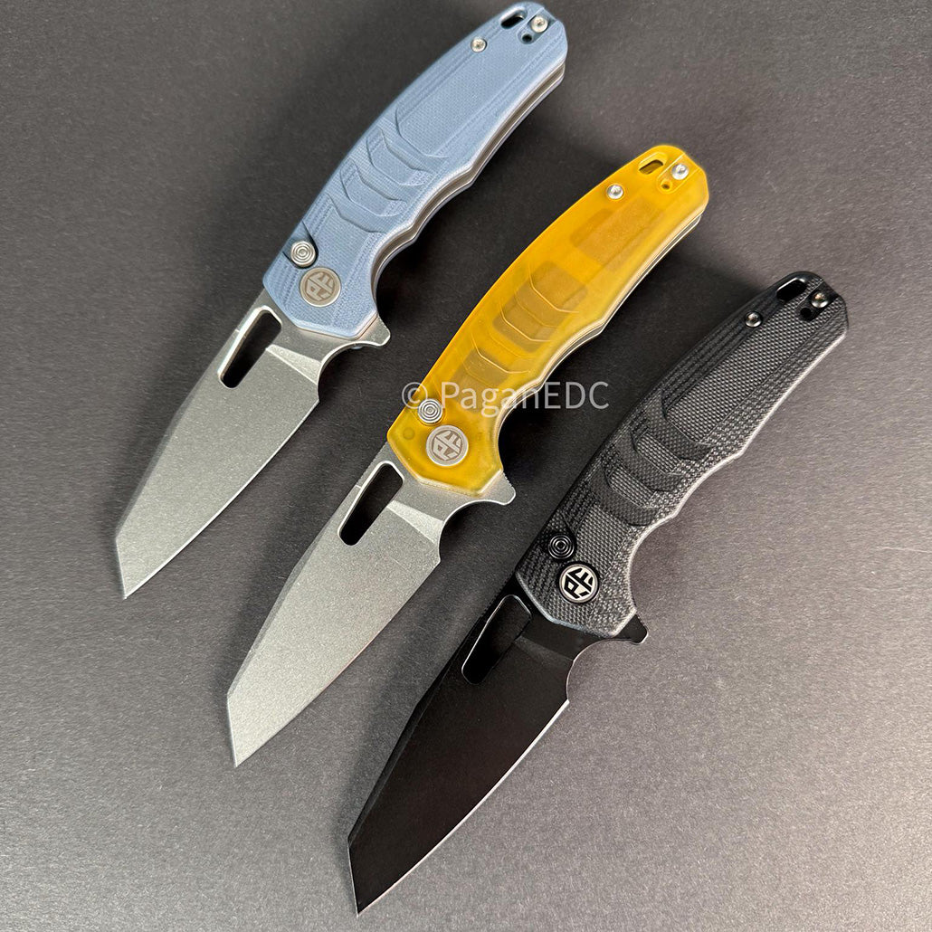Three Trilobite EDC folding knives with blue G10, yellow ULTEM, and black G10 handles, 14C28N steel blades, and button locks displayed on a gray background.