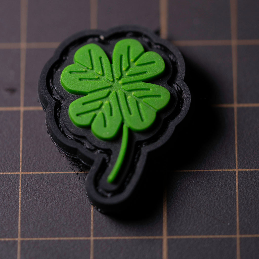 Small green PVC four-leaf clover patch on a black Velcro backing.