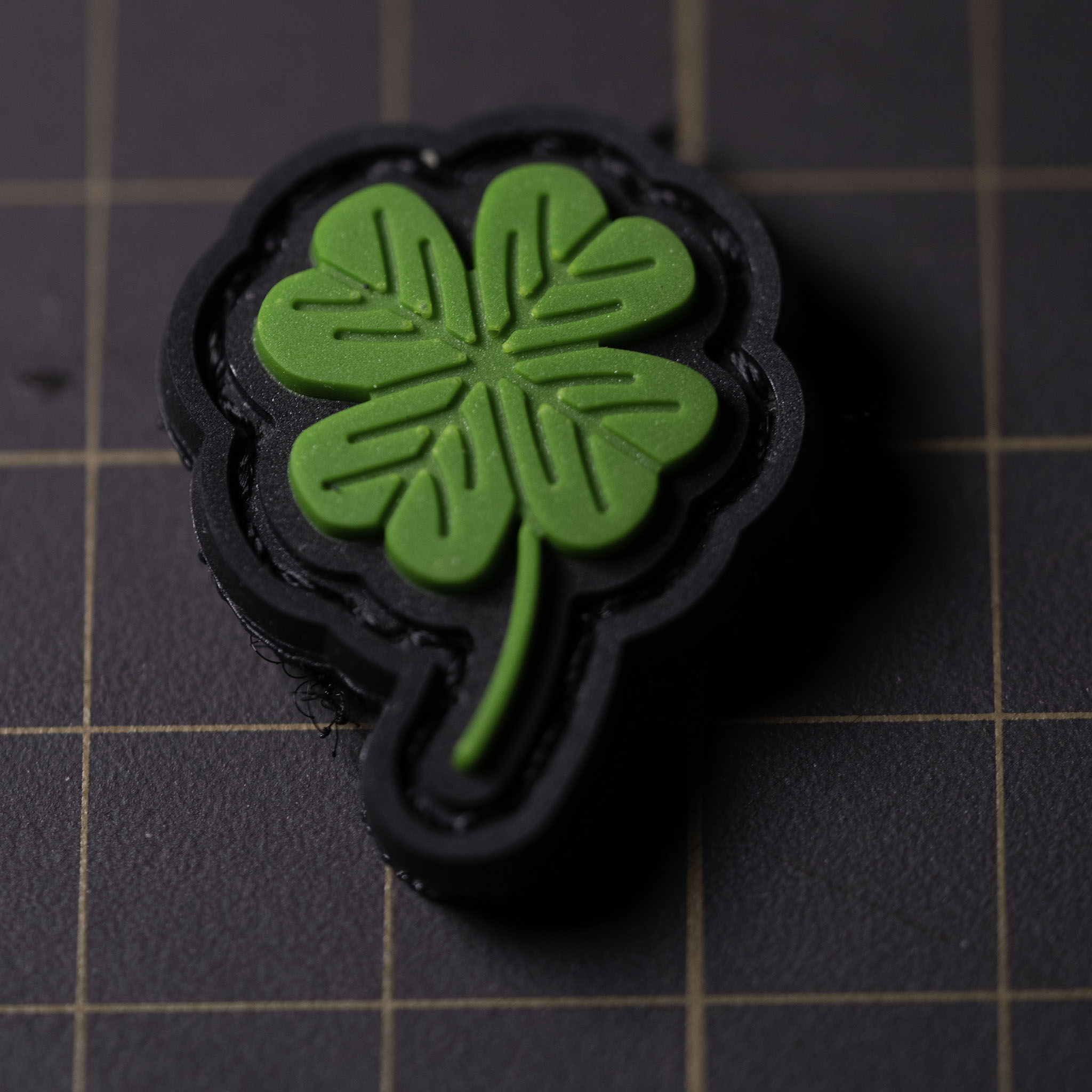 Small green PVC four-leaf clover patch on a black Velcro backing.