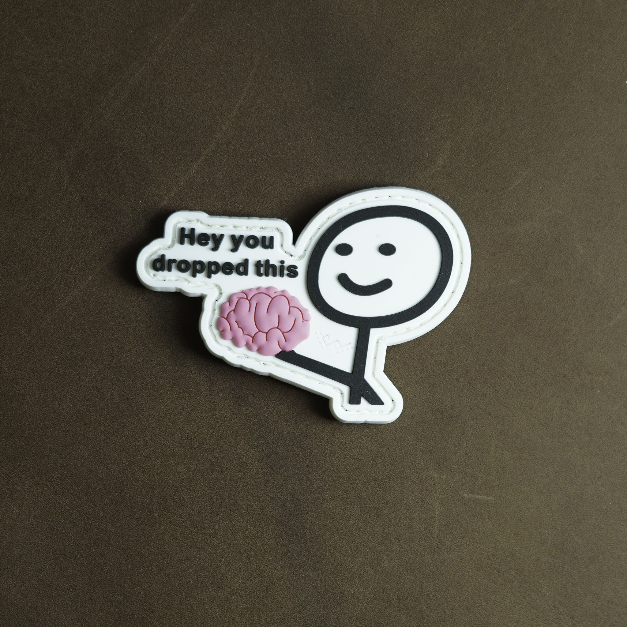 PVC patch showing a stick figure holding a pink brain with text “Hey you dropped this”.
