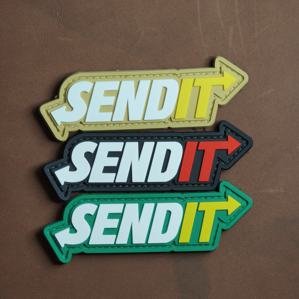 Three 'SEND IT' patches in different colors on a brown background