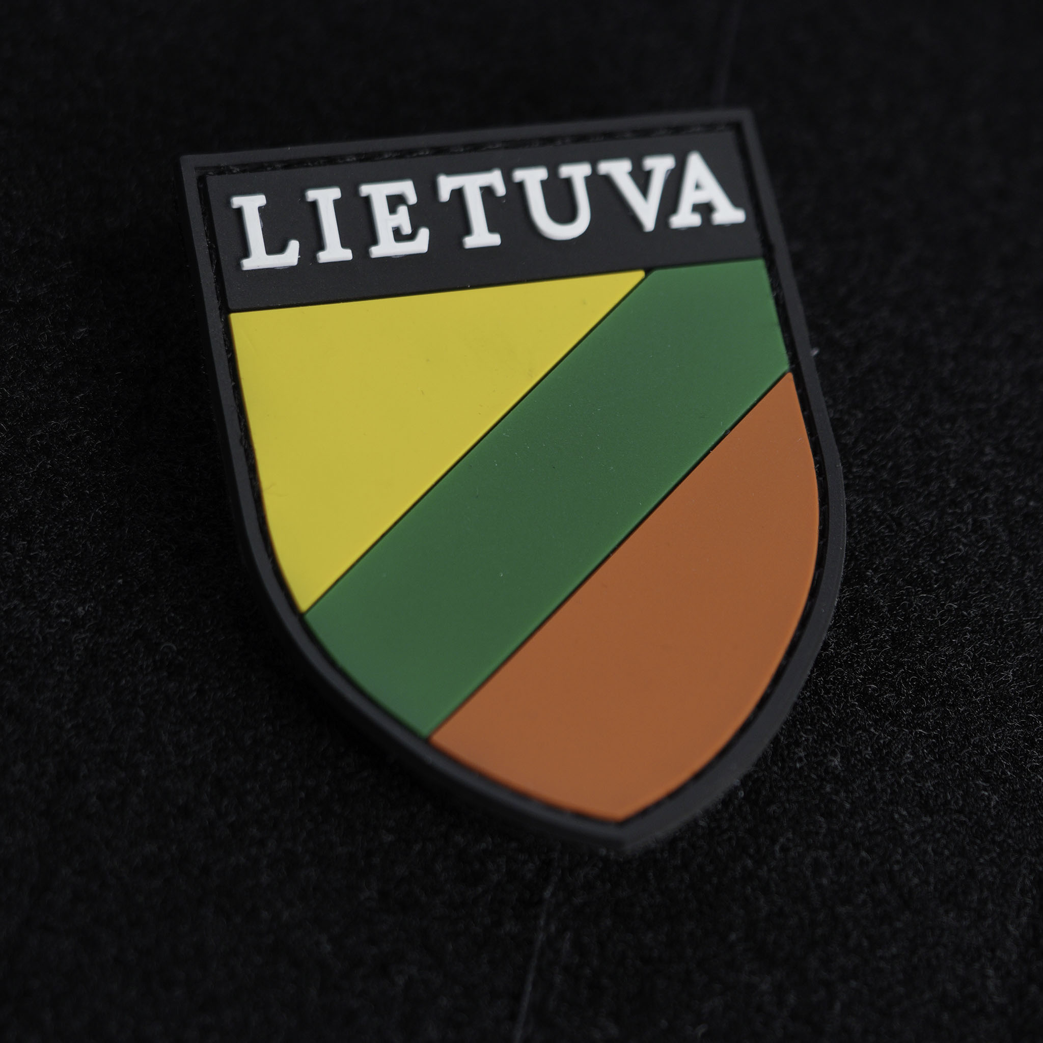 Taurus District Lithuanian partisan emblem PVC patch in green, yellow, and brown colors with Velcro backing on a dark background.