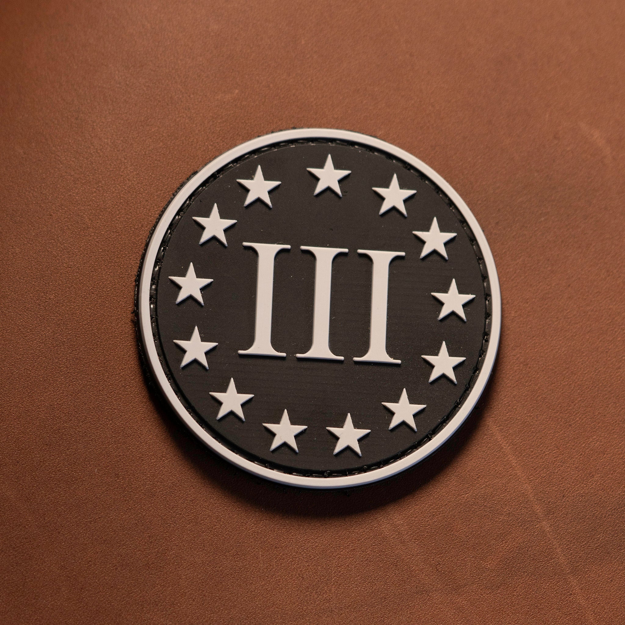 Round patch with number '3' and stars on a brown background